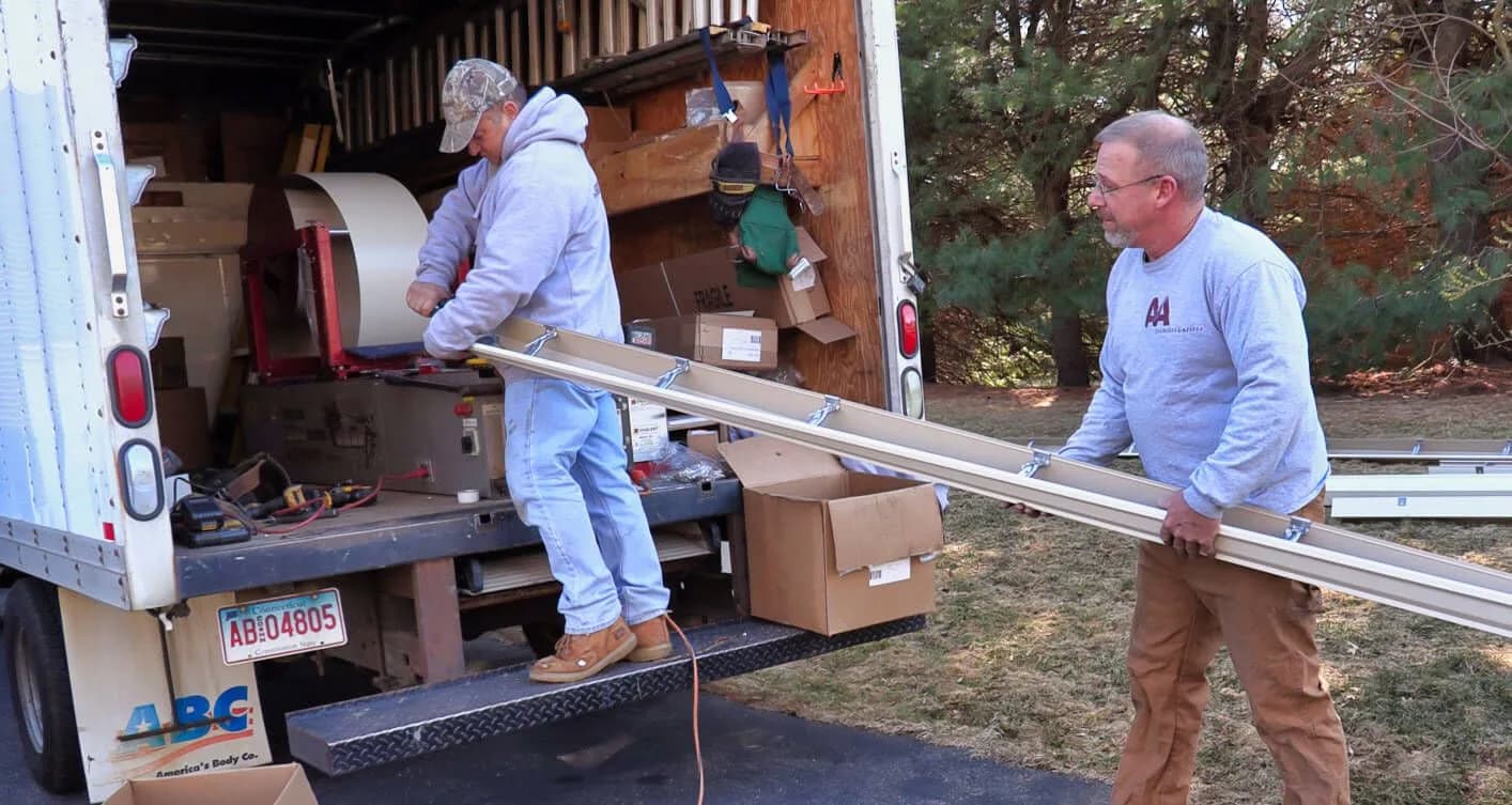A&A Seamless Gutters team loading custom-cut gutter sections from the mobile fabrication truck
