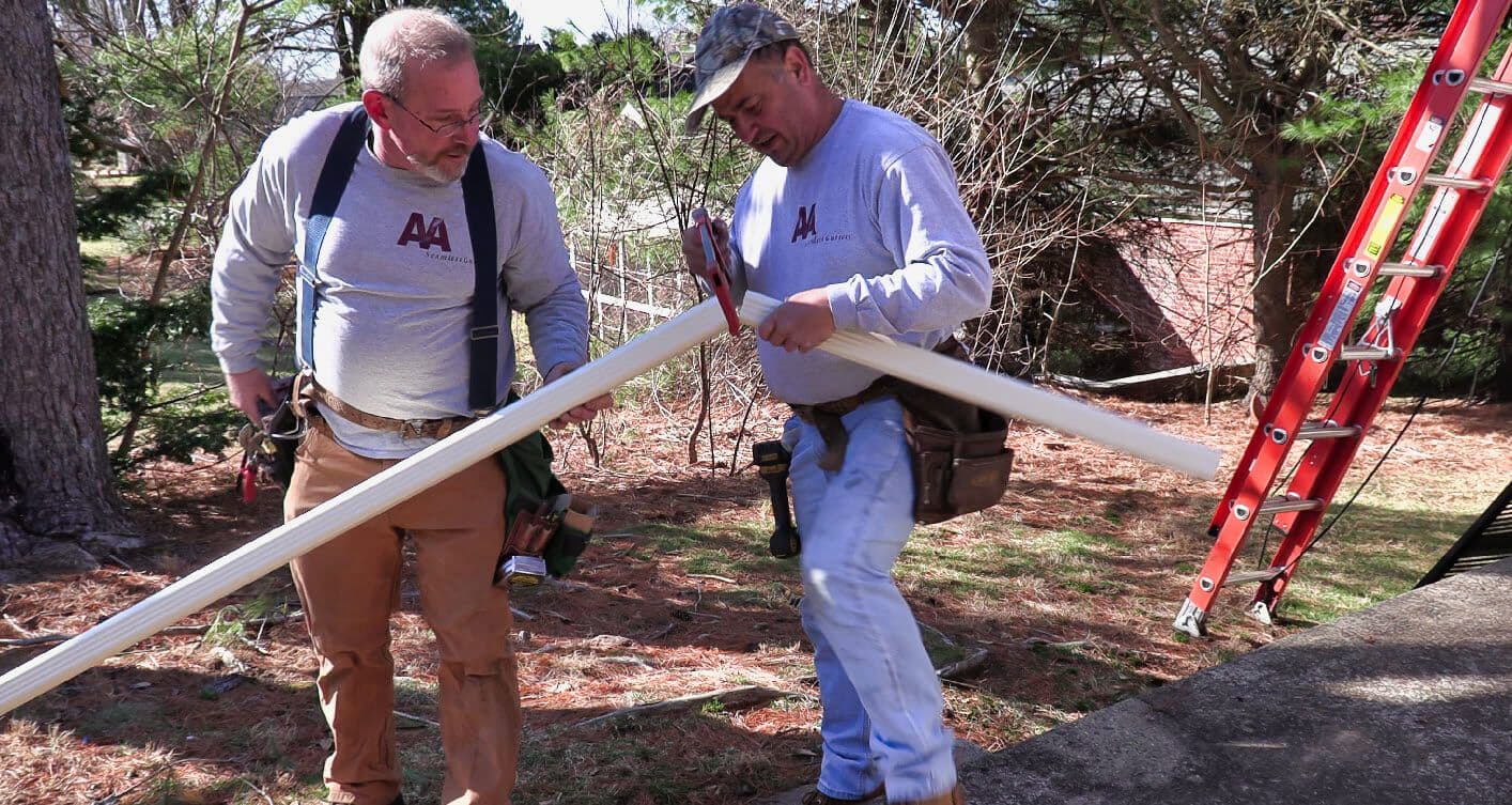 A&A Seamless Gutters team members carrying custom gutter sections