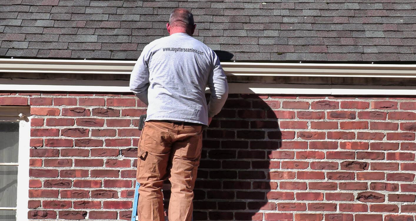 A&A worker on ladder securing gutters to fascia board